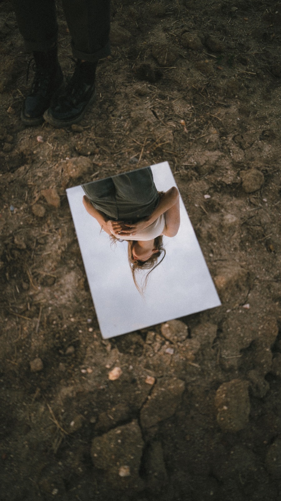 Reflejo de una mujer en un espejo sobre el suelo de un bosque
